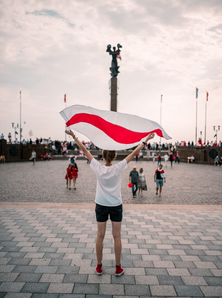 woman in white long sleeve shirt and black skirt holding white and red flag