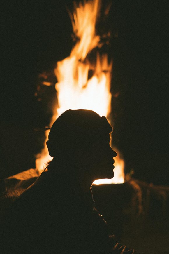 silhouette of man in front of bonfire