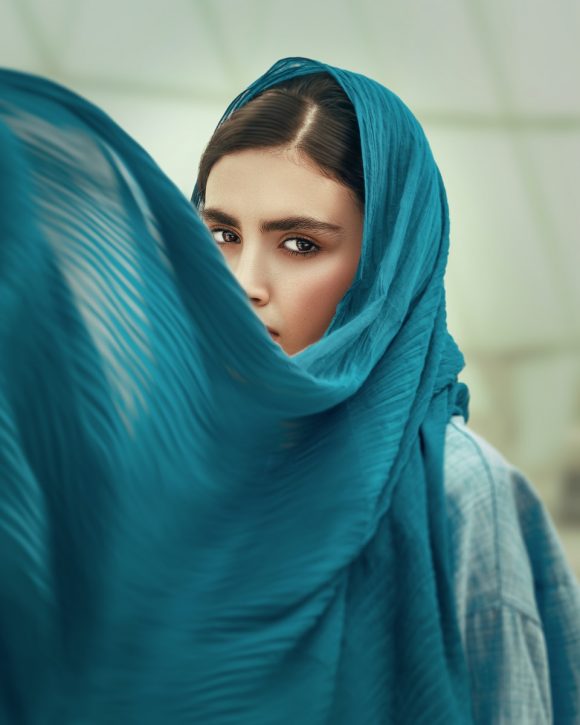 woman in blue hijab covering her face with blue textile